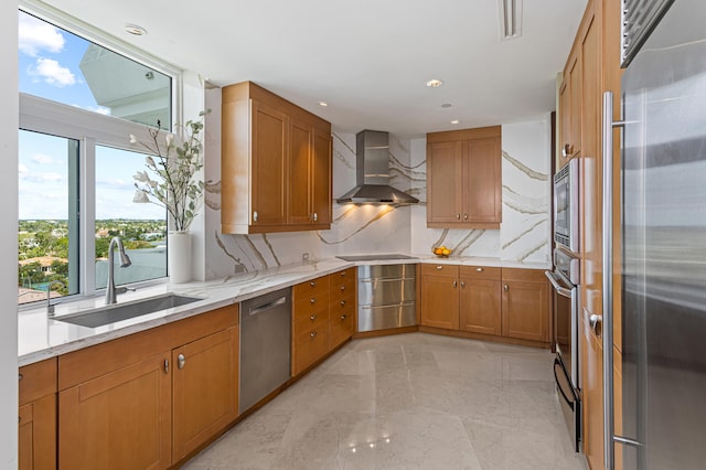 kitchen with wall chimney exhaust hood, stainless steel appliances, backsplash, sink, and light stone counters