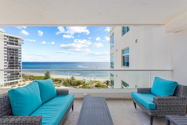 balcony with an outdoor living space, a water view, and a view of the beach