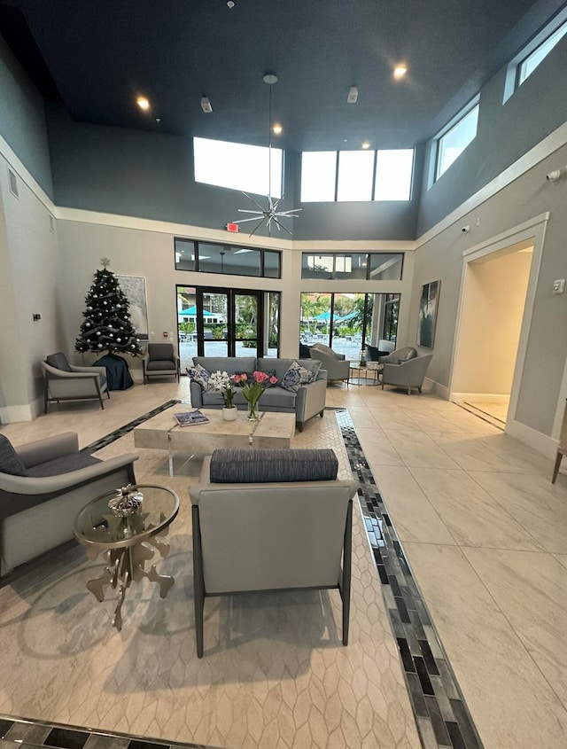 living room with french doors, ceiling fan, a towering ceiling, and light tile flooring