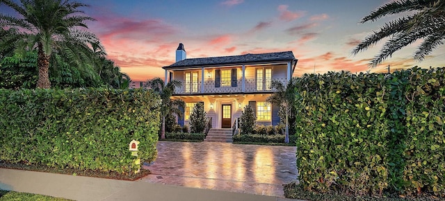 colonial-style house featuring a porch and a balcony