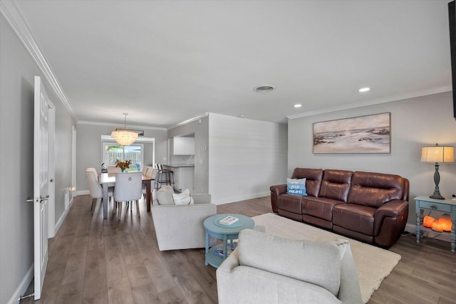 living room featuring light hardwood / wood-style floors, ornamental molding, and a notable chandelier