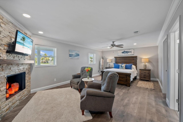 bedroom with a fireplace, hardwood / wood-style floors, ceiling fan, and crown molding