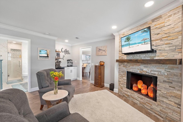 living room featuring a fireplace, light hardwood / wood-style floors, and crown molding