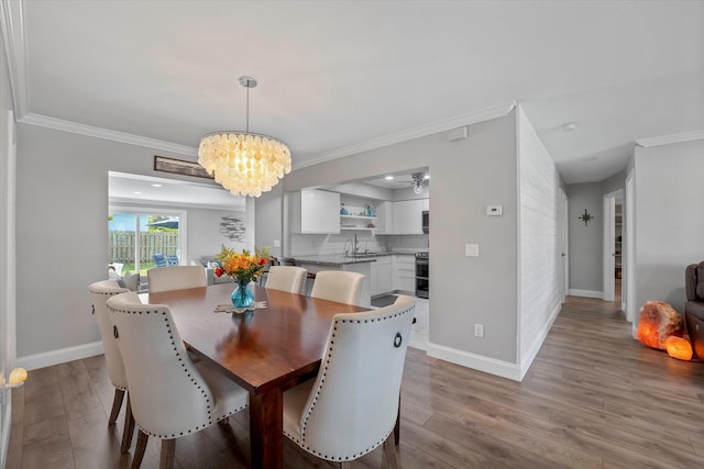 dining space featuring ornamental molding, hardwood / wood-style floors, a chandelier, and sink