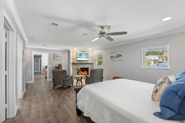 bedroom with crown molding, ceiling fan, a fireplace, and dark wood-type flooring