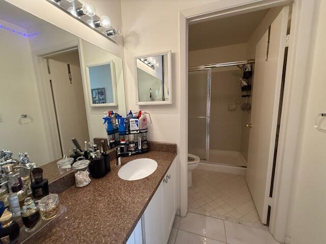 full bathroom featuring tile patterned flooring, a stall shower, toilet, and vanity