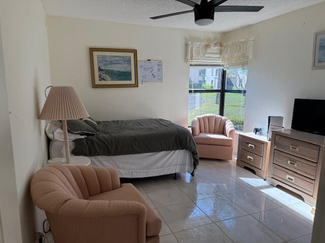 bedroom with light tile patterned floors, a ceiling fan, and a textured ceiling