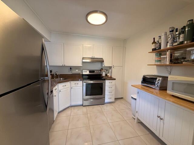 kitchen with light tile patterned floors, a toaster, stainless steel appliances, white cabinets, and under cabinet range hood