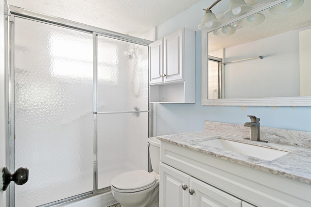 bathroom with vanity, toilet, an enclosed shower, and a textured ceiling