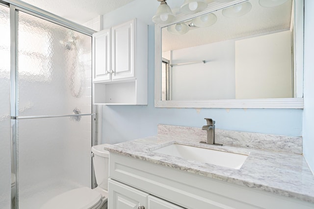 bathroom featuring vanity, a shower with door, and toilet