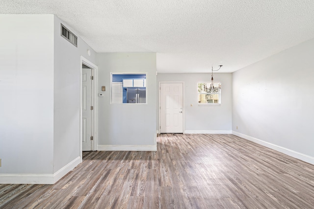 unfurnished living room with a textured ceiling, wood-type flooring, and a chandelier