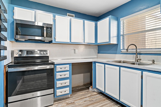 kitchen with light wood-type flooring, stainless steel appliances, sink, and white cabinets