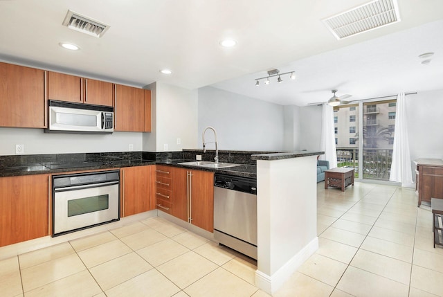 kitchen featuring sink, ceiling fan, dark stone countertops, appliances with stainless steel finishes, and track lighting