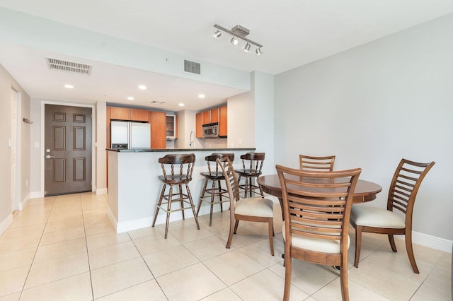 dining room featuring light tile flooring, track lighting, and sink