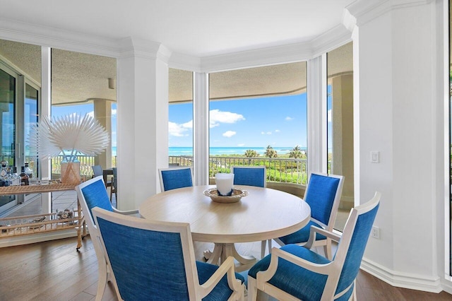 dining room featuring dark hardwood / wood-style floors, a water view, ornamental molding, and a healthy amount of sunlight