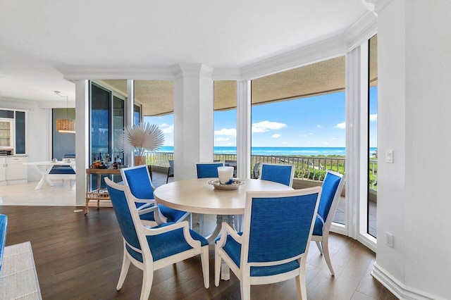 dining space with a water view, ornamental molding, and dark wood-type flooring