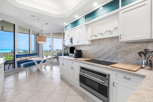 kitchen with decorative light fixtures, white cabinetry, backsplash, appliances with stainless steel finishes, and a raised ceiling