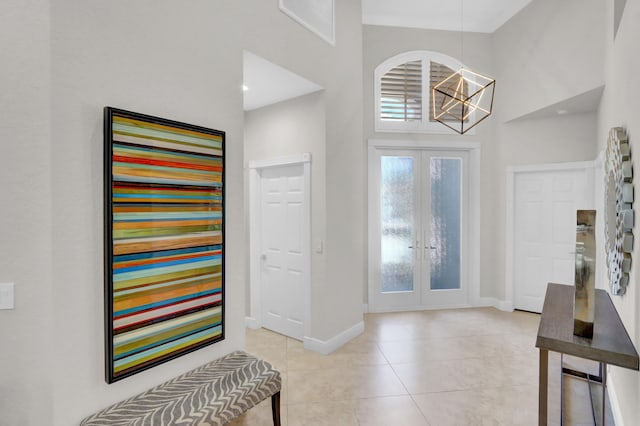 tiled entryway with a chandelier, french doors, and a high ceiling