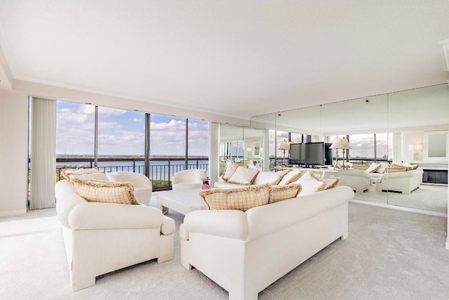 carpeted living room with a water view and a wall of windows