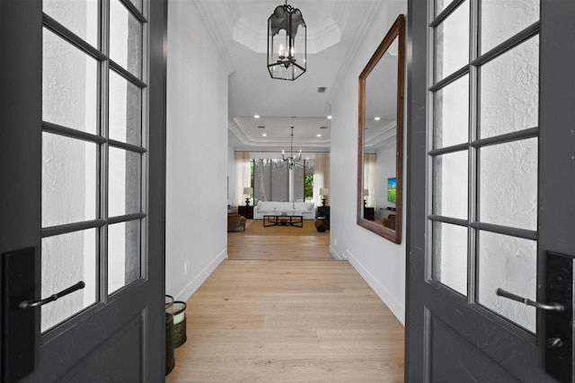 entryway with ornamental molding, an inviting chandelier, and light hardwood / wood-style floors