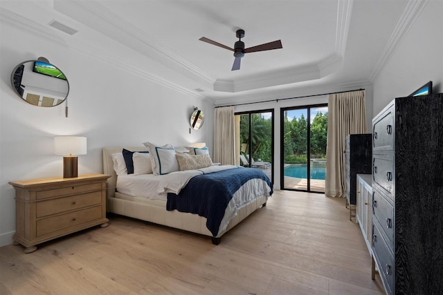 bedroom with light hardwood / wood-style flooring, ceiling fan, a tray ceiling, and ornamental molding