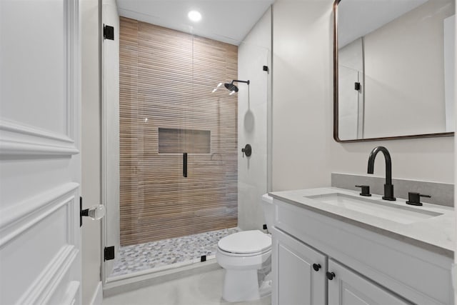 bathroom featuring vanity with extensive cabinet space, toilet, and a shower with door