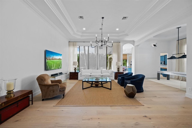 living room with light hardwood / wood-style flooring, a tray ceiling, and an inviting chandelier