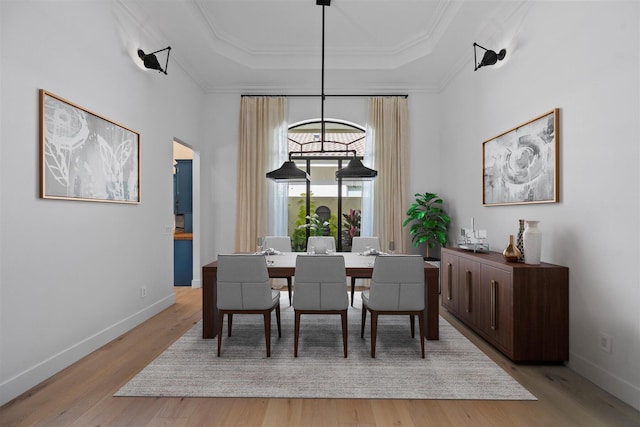 dining space featuring light hardwood / wood-style floors and a raised ceiling