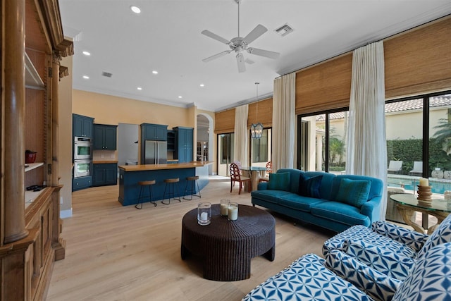 living room featuring ceiling fan, crown molding, and light wood-type flooring