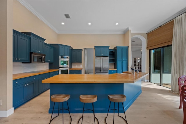 kitchen featuring butcher block countertops, appliances with stainless steel finishes, light hardwood / wood-style flooring, and a breakfast bar area