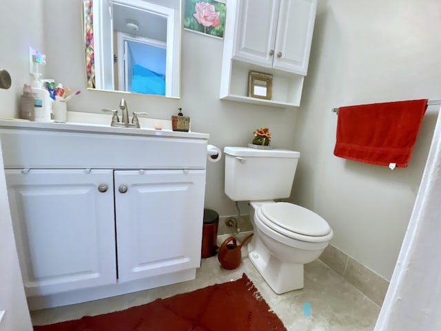 bathroom featuring toilet, vanity, and tile flooring