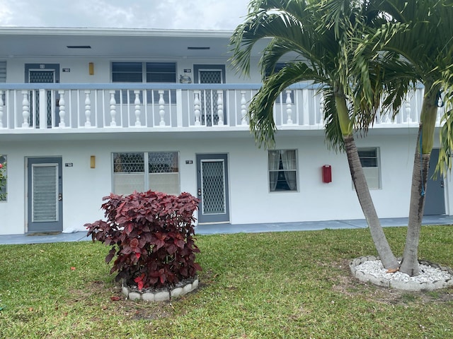 view of front of house with a balcony and a front yard