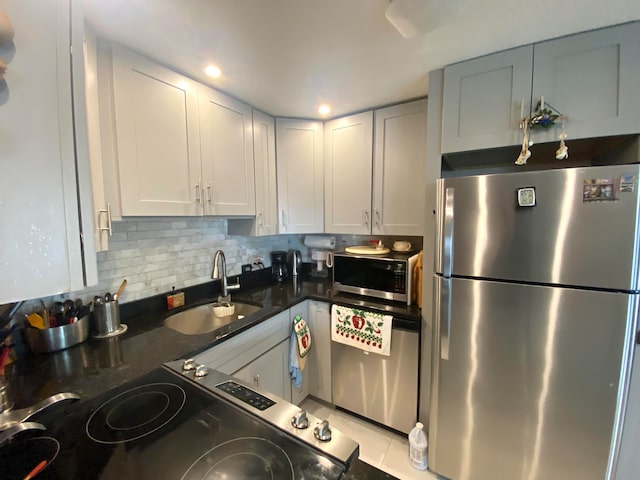 kitchen with sink, light tile floors, dark stone counters, stainless steel appliances, and tasteful backsplash