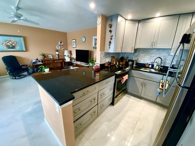 kitchen with kitchen peninsula, ceiling fan, sink, appliances with stainless steel finishes, and backsplash