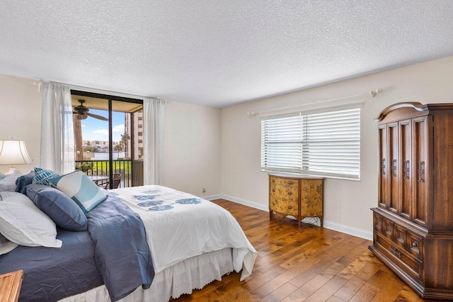 bedroom featuring a textured ceiling, multiple windows, access to outside, and dark hardwood / wood-style flooring