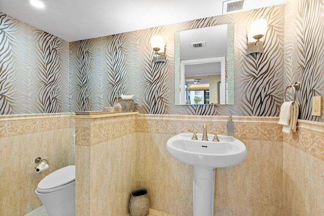 bathroom with backsplash, toilet, and tile walls