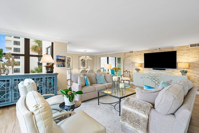 living room featuring light wood-type flooring, crown molding, and a chandelier