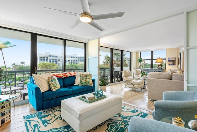 living room with ceiling fan, light hardwood / wood-style flooring, and a wall of windows