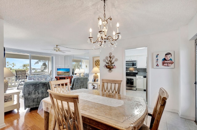 tiled dining area featuring a textured ceiling and ceiling fan with notable chandelier