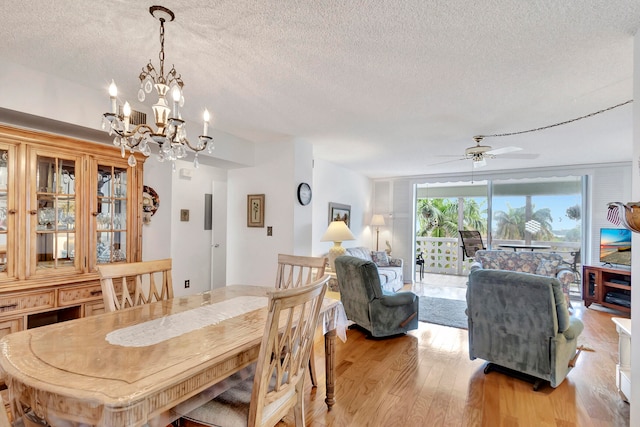 dining room featuring ceiling fan with notable chandelier, a textured ceiling, and light wood-type flooring