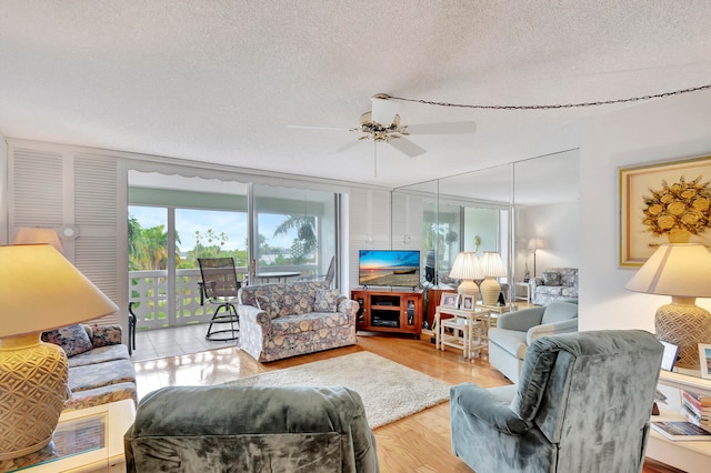 living room featuring light wood-type flooring, a textured ceiling, and ceiling fan