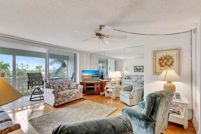 living room with ceiling fan, a textured ceiling, and light hardwood / wood-style flooring