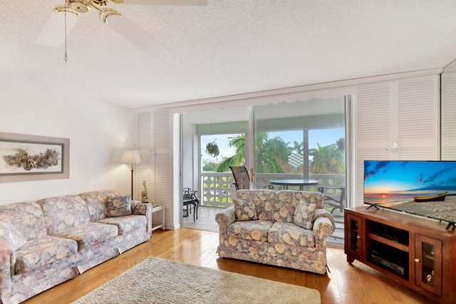 living room with ceiling fan, a textured ceiling, and light hardwood / wood-style floors