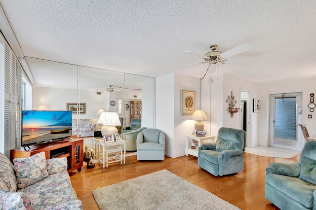 living room with hardwood / wood-style floors, ceiling fan, and a textured ceiling