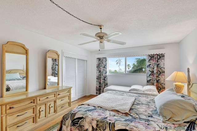 bedroom featuring ceiling fan, a textured ceiling, and light wood-type flooring