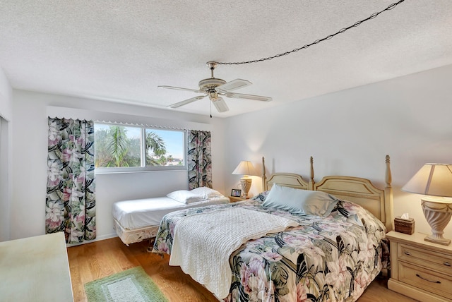 bedroom featuring hardwood / wood-style floors, ceiling fan, and a textured ceiling