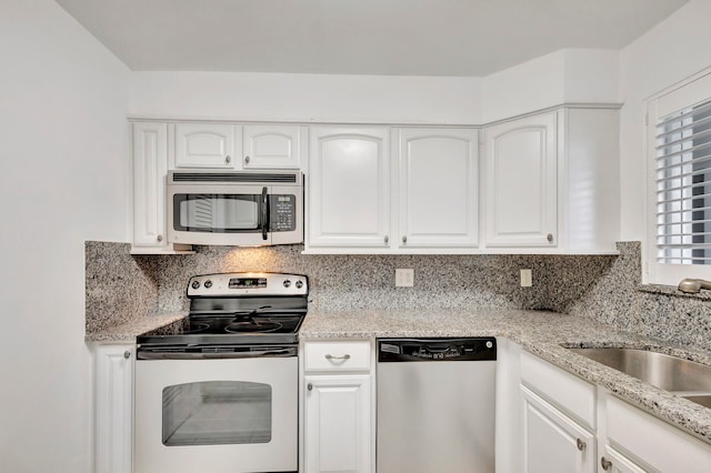 kitchen featuring stainless steel appliances, white cabinets, decorative backsplash, sink, and light stone countertops