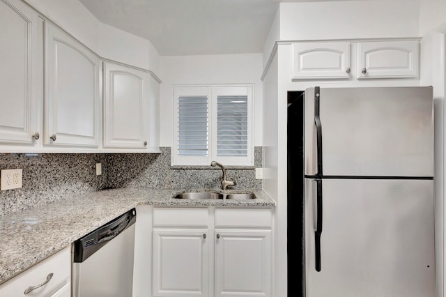 kitchen with white cabinetry, sink, appliances with stainless steel finishes, light stone countertops, and decorative backsplash