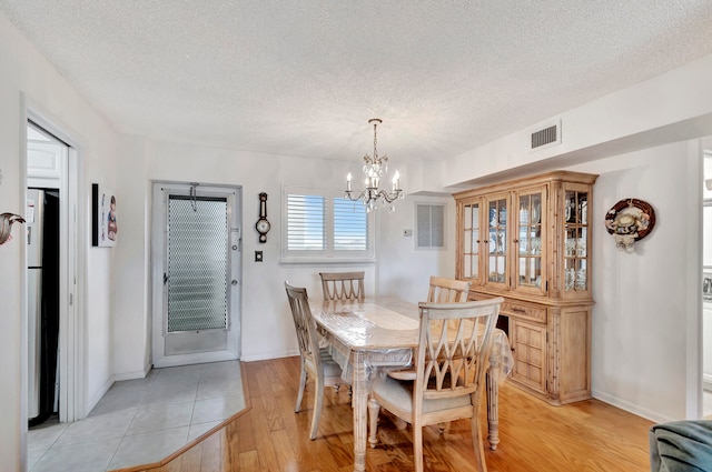 dining area featuring a textured ceiling, light wood-type flooring, and a chandelier