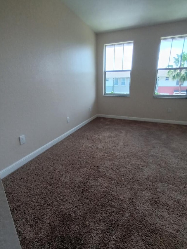 spare room featuring a healthy amount of sunlight and dark carpet